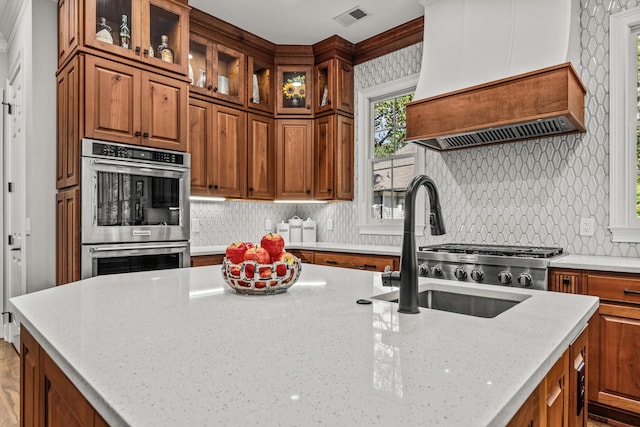 kitchen with sink, backsplash, custom exhaust hood, light stone counters, and stainless steel double oven