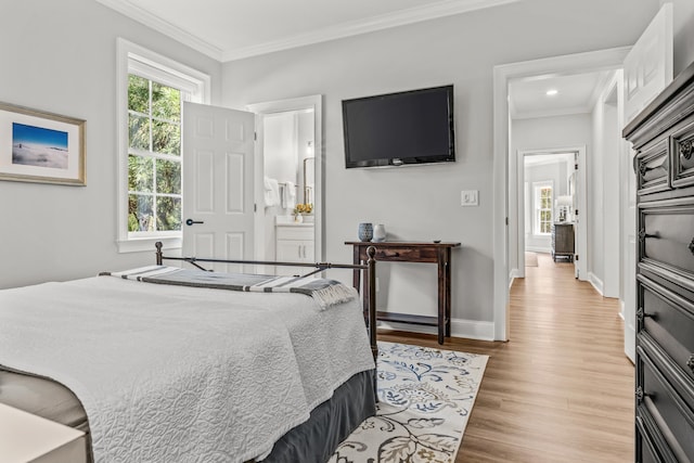 bedroom with crown molding, connected bathroom, multiple windows, and light hardwood / wood-style flooring