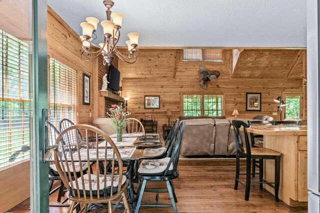 dining area with hardwood / wood-style flooring, a textured ceiling, a notable chandelier, and wooden walls