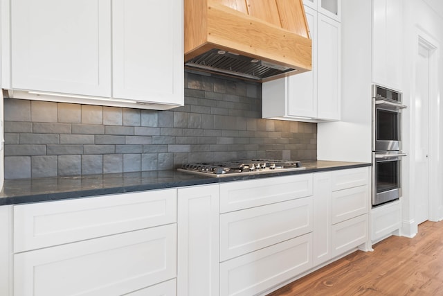 1358 Veranda Park Dr, Madison, GA 30650 - kitchen featuring custom exhaust hood, stainless steel appliances, dark countertops, glass insert cabinets, and white cabinetry