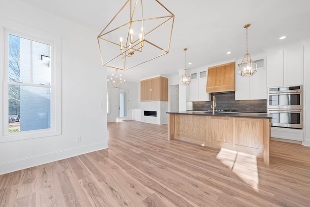1358 Veranda Park Dr, Madison, GA 30650 - kitchen with stainless steel double oven, white cabinetry, backsplash, dark countertops, and decorative light fixtures