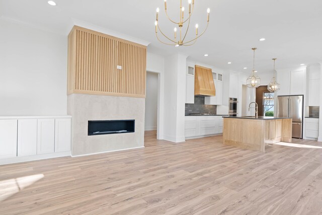 1358 Veranda Park Dr, Madison, GA 30650 - kitchen featuring stainless steel appliances, open floor plan, custom range hood, an island with sink, and pendant lighting