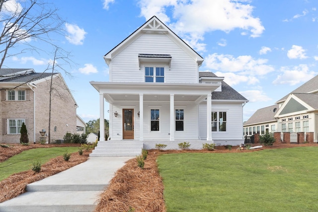 view of front of house with covered porch, roof with shingles, and a front yard