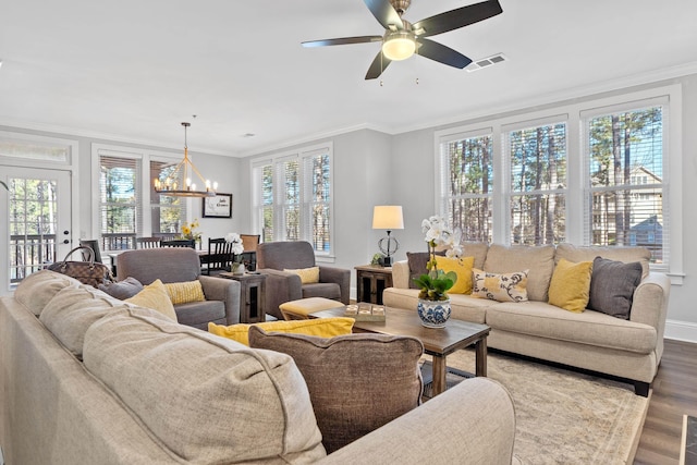 living room featuring hardwood / wood-style flooring, ceiling fan with notable chandelier, ornamental molding, and a healthy amount of sunlight