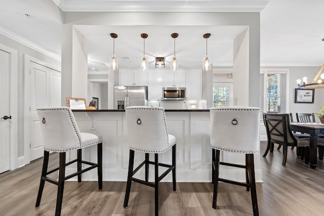 kitchen with white cabinetry, pendant lighting, a kitchen breakfast bar, and appliances with stainless steel finishes