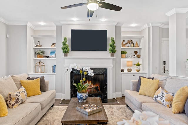 living room with built in shelves, ornamental molding, a premium fireplace, and hardwood / wood-style flooring