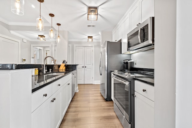 kitchen with white cabinetry, decorative light fixtures, crown molding, and appliances with stainless steel finishes