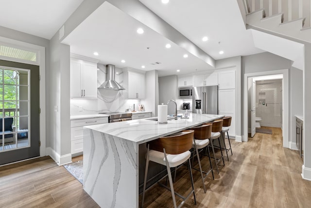 1010F Tailwater, Greensboro, GA 30642 - kitchen featuring wall chimney range hood, a sink, light wood-style floors, stainless steel appliances, and a large island