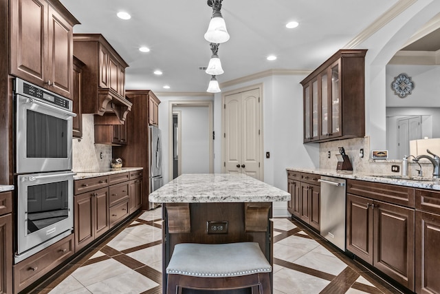 kitchen featuring dark brown cabinetry, decorative light fixtures, ornamental molding, appliances with stainless steel finishes, and backsplash