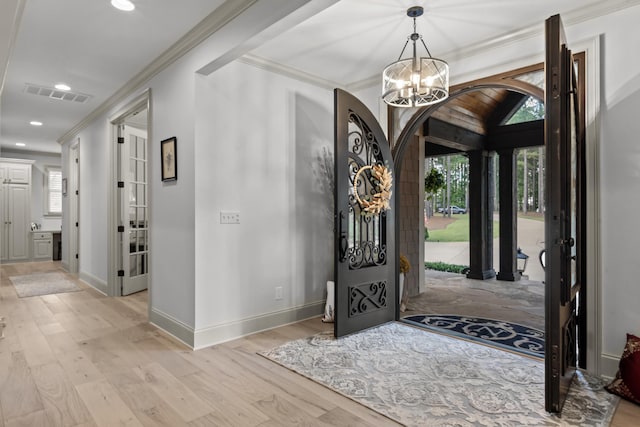 foyer featuring ornamental molding, light hardwood / wood-style floors, and a notable chandelier