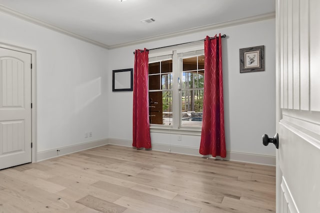 spare room featuring ornamental molding and light hardwood / wood-style floors