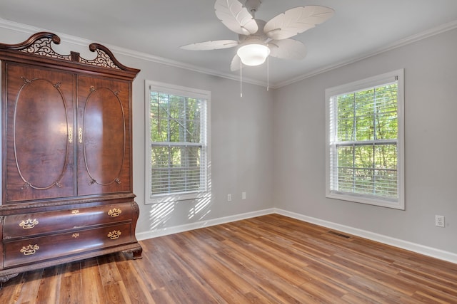 unfurnished bedroom with multiple windows, crown molding, hardwood / wood-style floors, and ceiling fan