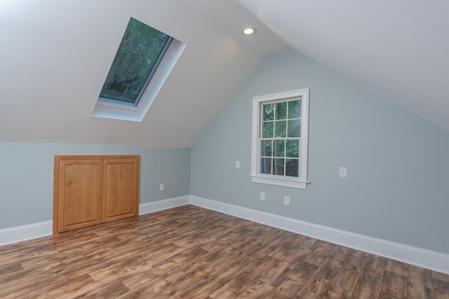 additional living space featuring lofted ceiling with skylight and hardwood / wood-style floors