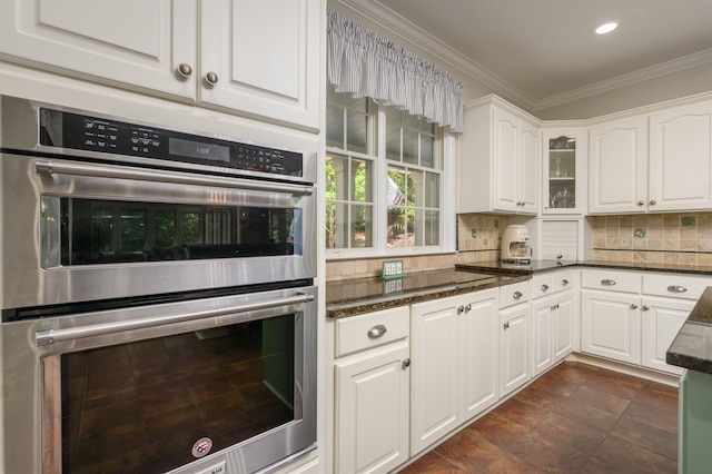 kitchen with tasteful backsplash, ornamental molding, white cabinets, and double oven