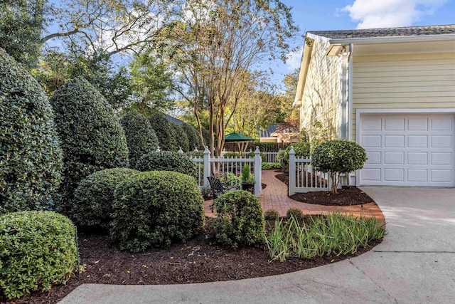 view of home's exterior featuring concrete driveway, a garage, and fence
