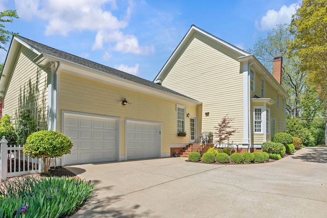 view of home's exterior with a chimney, a garage, and concrete driveway
