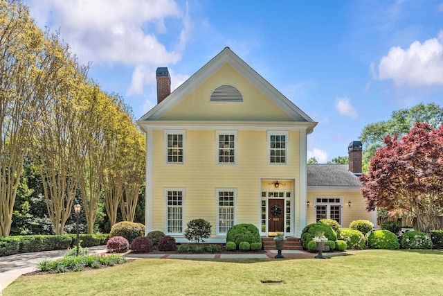 view of front facade with a front yard and a chimney