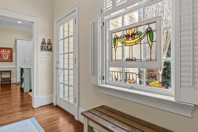 doorway featuring wood finished floors, baseboards, and ornamental molding