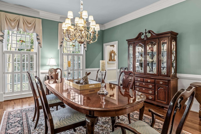 dining area with wainscoting, an inviting chandelier, ornamental molding, and wood finished floors