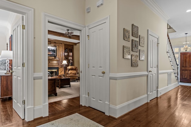 interior space featuring baseboards, an inviting chandelier, dark wood-style floors, crown molding, and stairs
