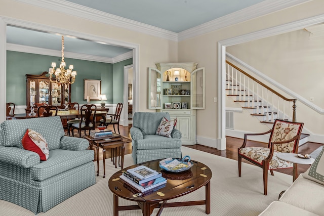 living room with a chandelier, stairway, ornamental molding, and wood finished floors