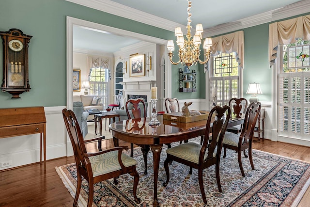 dining space featuring ornamental molding, a wainscoted wall, and a notable chandelier
