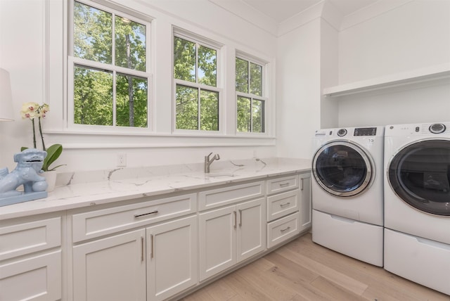1100 Neary Rdg, Greensboro, GA 30642 - laundry room featuring cabinet space, light wood-style flooring, washing machine and clothes dryer, and a sink