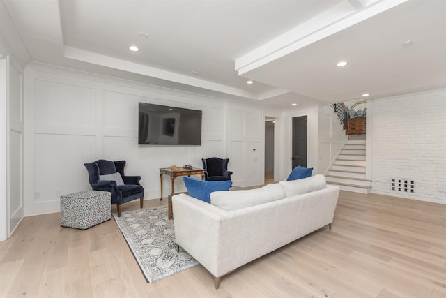 1100 Neary Rdg, Greensboro, GA 30642 - living room with a decorative wall, stairs, light wood-type flooring, a tray ceiling, and recessed lighting