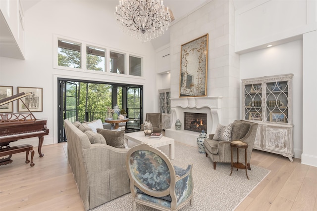 1100 Neary Rdg, Greensboro, GA 30642 - living area with a warm lit fireplace, light wood-style flooring, a towering ceiling, and an inviting chandelier