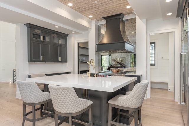1100 Neary Rdg, Greensboro, GA 30642 - kitchen featuring recessed lighting, light countertops, light wood-type flooring, a kitchen island with sink, and custom exhaust hood
