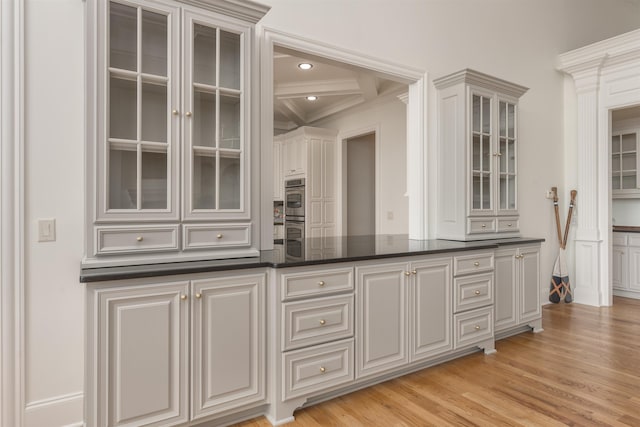 1191 Cory Cir, Greensboro, GA 30642 - kitchen with dark countertops, glass insert cabinets, ornamental molding, stainless steel double oven, and light wood-style flooring