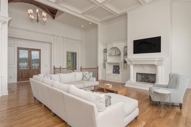 1191 Cory Cir, Greensboro, GA 30642 - living area featuring a towering ceiling, crown molding, light wood finished floors, a chandelier, and a fireplace with raised hearth
