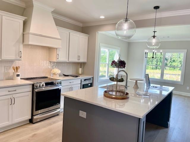 kitchen featuring custom exhaust hood, white cabinetry, stainless steel electric range, pendant lighting, and a kitchen island with sink