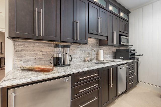 kitchen with sink, backsplash, light stone countertops, and appliances with stainless steel finishes