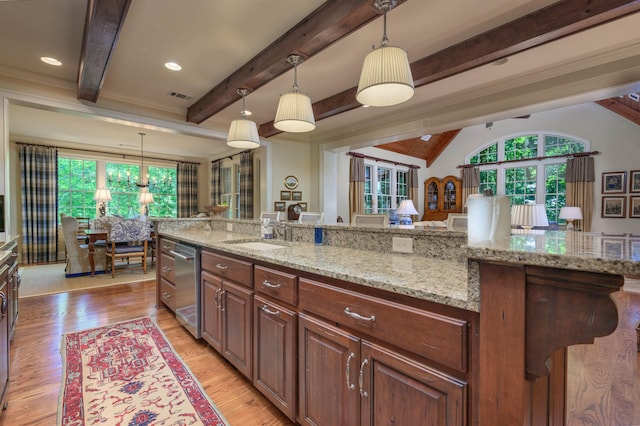 kitchen with pendant lighting, sink, stainless steel dishwasher, light stone counters, and light hardwood / wood-style floors