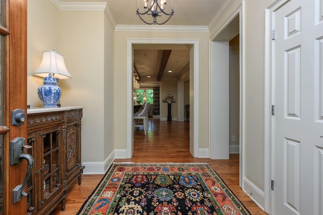 hall with ornamental molding, hardwood / wood-style floors, and an inviting chandelier