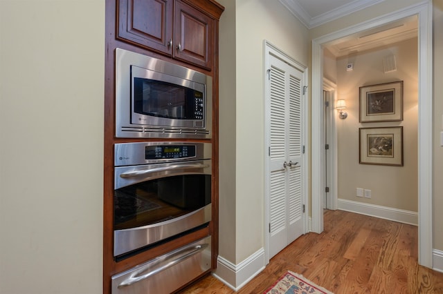clothes washing area featuring crown molding, stacked washer / drying machine, and light hardwood / wood-style floors