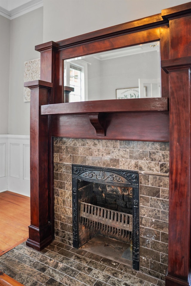 interior details with a tiled fireplace, hardwood / wood-style floors, and crown molding