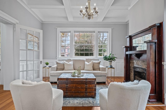 living room featuring coffered ceiling, a notable chandelier, beam ceiling, and light hardwood / wood-style flooring