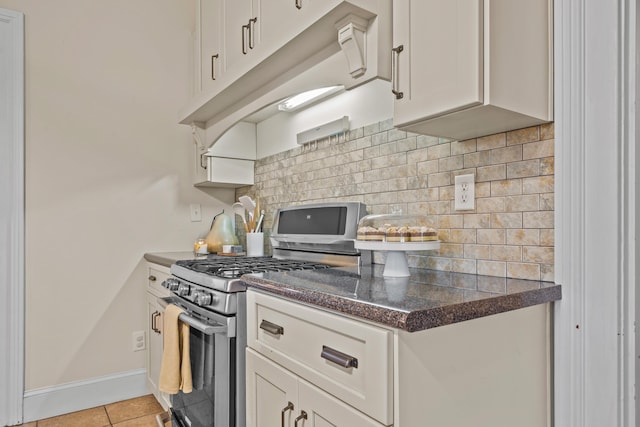 kitchen featuring white cabinetry, stainless steel range with gas cooktop, light tile patterned floors, and backsplash