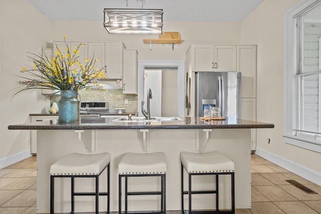 kitchen with white cabinetry, a breakfast bar, decorative backsplash, and stainless steel fridge with ice dispenser