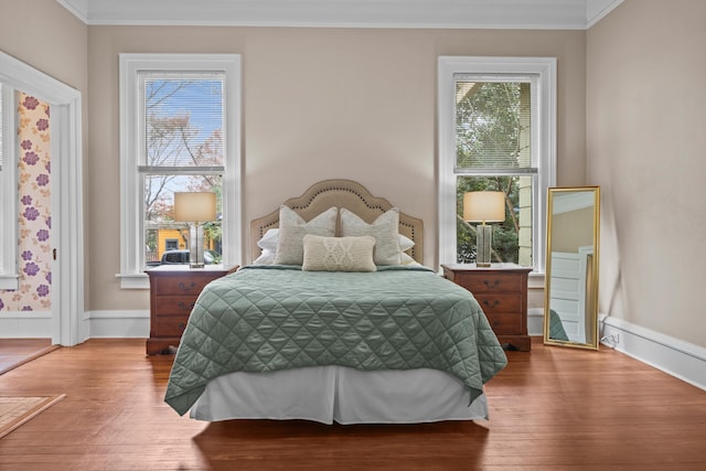 bedroom with multiple windows, ornamental molding, and hardwood / wood-style flooring