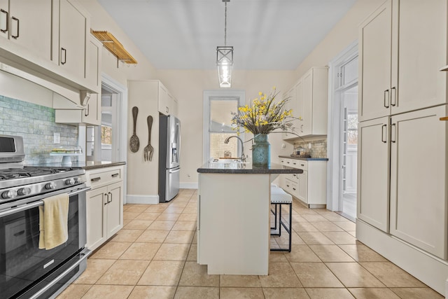 kitchen featuring stainless steel appliances, a breakfast bar, a kitchen island with sink, and white cabinets