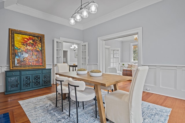 dining space with crown molding, a chandelier, french doors, and hardwood / wood-style flooring