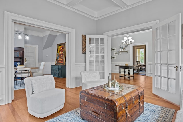 living area featuring light hardwood / wood-style flooring, beam ceiling, coffered ceiling, a notable chandelier, and ornamental molding