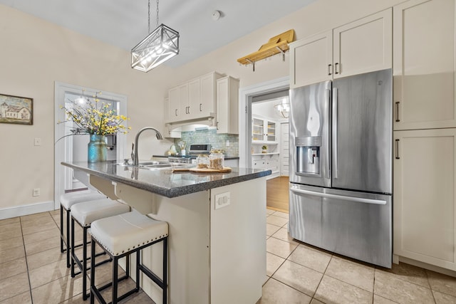 kitchen with a kitchen island, sink, white cabinets, decorative backsplash, and stainless steel fridge with ice dispenser