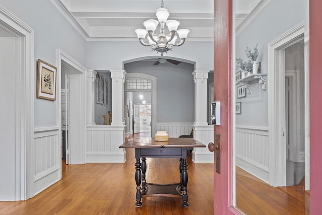 hallway featuring ornate columns, a notable chandelier, and light hardwood / wood-style flooring