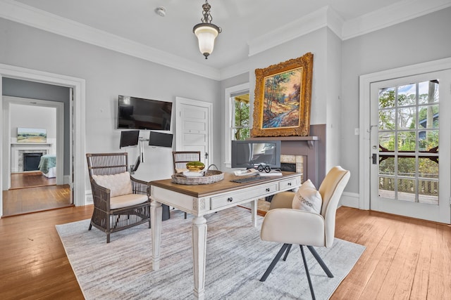 home office with light hardwood / wood-style flooring, a wealth of natural light, and a fireplace