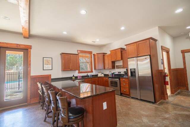 kitchen featuring appliances with stainless steel finishes, sink, dark stone countertops, a kitchen breakfast bar, and kitchen peninsula