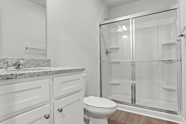 bathroom featuring vanity, hardwood / wood-style floors, a shower with door, and toilet